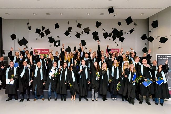 Glückliche Absolventen lassen ihre Hüte fliegen
