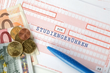Ein Überweisungsschein ist zu sehen, auf dem ein Stift und Geld liegen