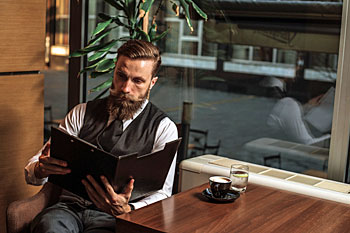 Promotionsstudent sind mit Buch in einem Cafe.