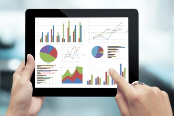 Eine Person hält ein Tablet in den Händen und schaut sich verschiedene Infografiken an