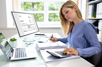 Buchhalterin sitzt am Schreibtisch und prüft Rechnungen