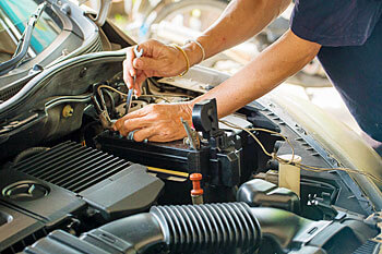 Hände arbeiten an einem Automotor im Fahrzeugtechnik Fernstudium