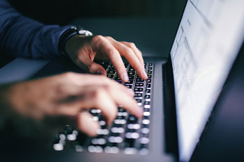 Kriminologe sitzt am Laptop