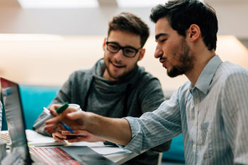 Zwei Informatiker sitzen am Computer und sprechen über ein Projekt