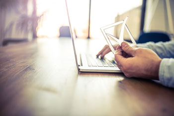 Fernstudent für Wirtschaftsinformatik sitzt zu Hause am Laptop und prüft die Zulassungsvoraussetzungen