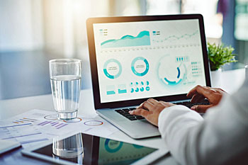 Schreibtisch mit Laptop, Tablet und Unterlagen.