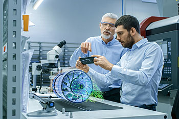 Zwei Männer vor einer elektrotechnischen Anlage.