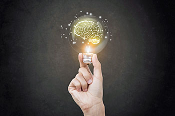 Hand die eine Glühbirne hält, in der ein Gehirn-Symbol leuchtet.