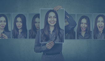 Eine Frau hält ein Bild von sich mit lachendem Gesicht. Im Hintergrund eine Reihe von Bildern mit verschiedenen Gesichtsausdrücken.