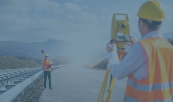 Zwei Ingenieure in Schutzwesten- und helmen bei der Straßenvermessung.