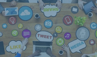 Vogelperspektive auf einen Schreibtisch mit verschiedenen medialen Icons und Sprechblasen.