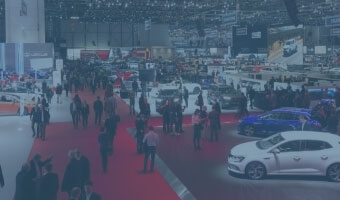 Eine Messehalle mit Autos und Menschen.