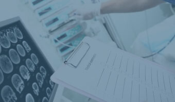 Ein Arzt mit einem Klemmbrett wertet MRT-Bilder auf einem Monitor aus.