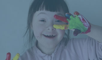 Ein lachendes Kind mit Fingerfarbe an den Händen.