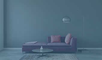 Ein kahler Raum mit Sofa, rundem Abstelltisch auf einem Teppich und eine Stehlampe. 