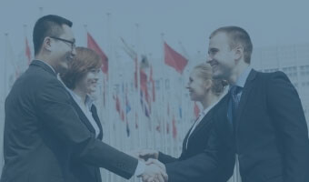 Zwei europäische Manager schütteln zwei asiatischen Managern die Hand.