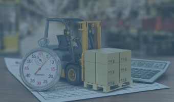 Auf einem Schreibtisch stehen ein Miniatur-Gabelstapler, eine Stoppuhr und ein Taschenrechner.