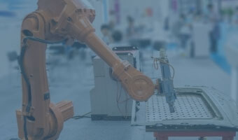 Ein orangefarbener Roboterarm arbeitet in einer Fabrikhalle. 