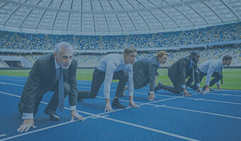 Fünf Manager in Hemd und Anzug stehen in einem Sportstadion in Startposition für ein Rennen.