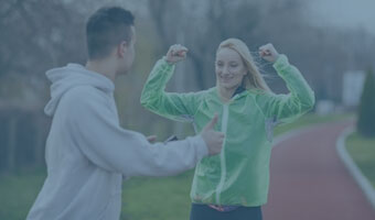 Auf einer Rennbahn misst ein Mann die Zeit einer Läuferin.