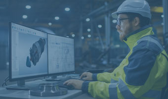 Ein Techniker mit gelber Sicherheitsjacke und -helm arbeitet an einem Rechner.