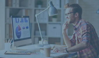 Ein junger Mann arbeitet an einem Schreibtisch und analysiert verschiedene Diagramme.