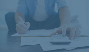 Ein Volkswirtschaftler sitzt auf dem Boden und arbeitet mit dem Taschenrechner.