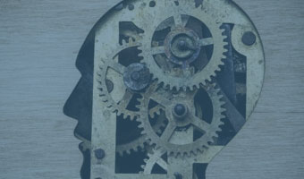 Ein Passepartout, in Form eines menschlichen Kopfes im Profil, zeigt ein Werk aus Zahnrädern.
